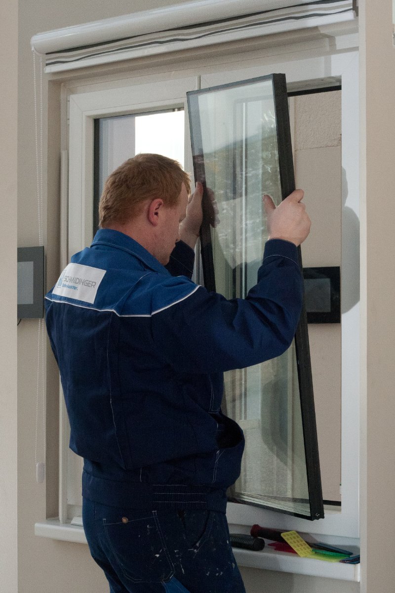 Glaser hebt die alte Isolierglasscheibe aus dem Kunststofffensterflügel