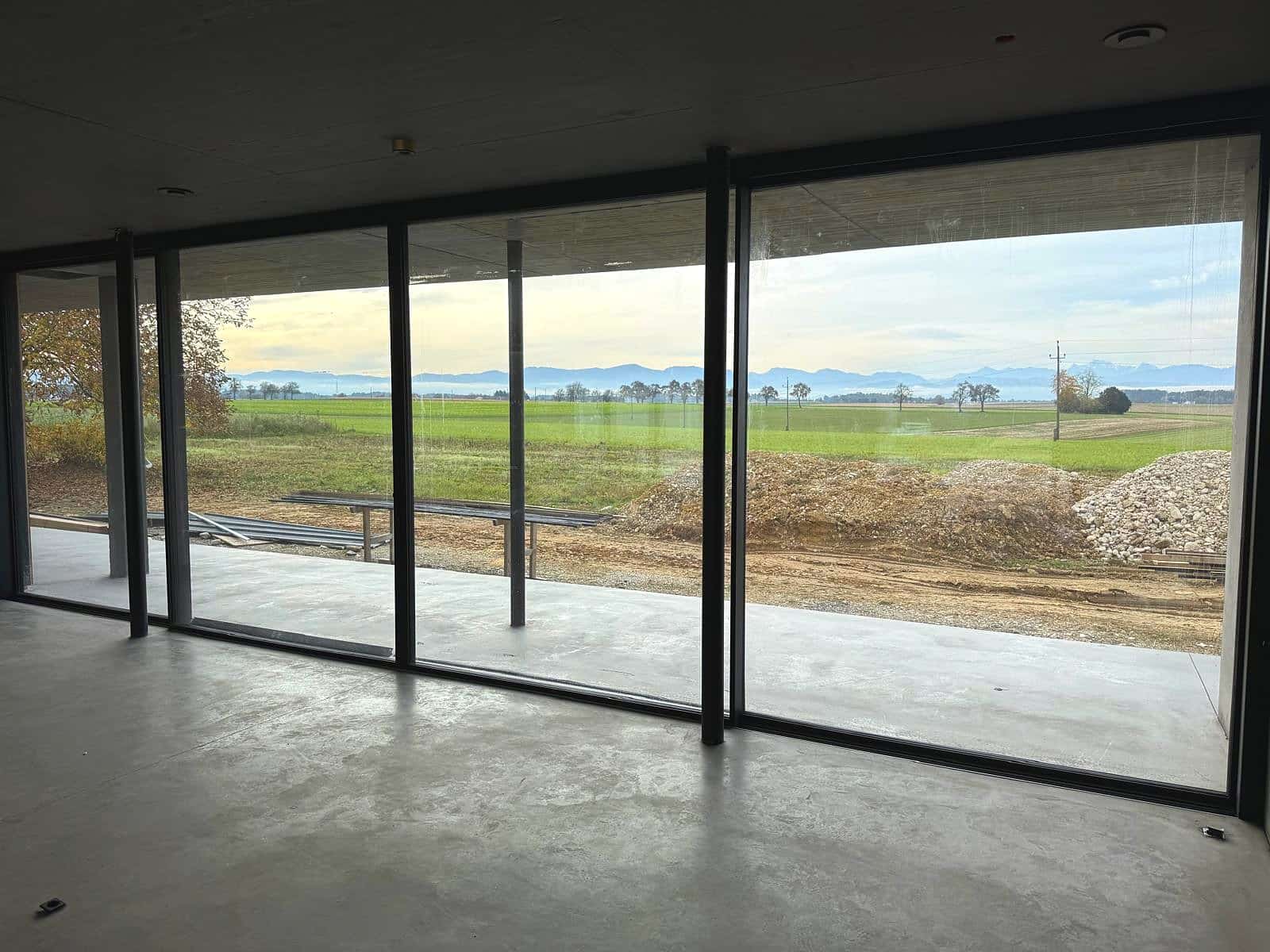 Große wärmegedämmte Aluminium-Schiebefenster mit schmalen Profilen im Rohbau eines Neubaus, Blick über Felder auf die Alpen, Oberösterreich