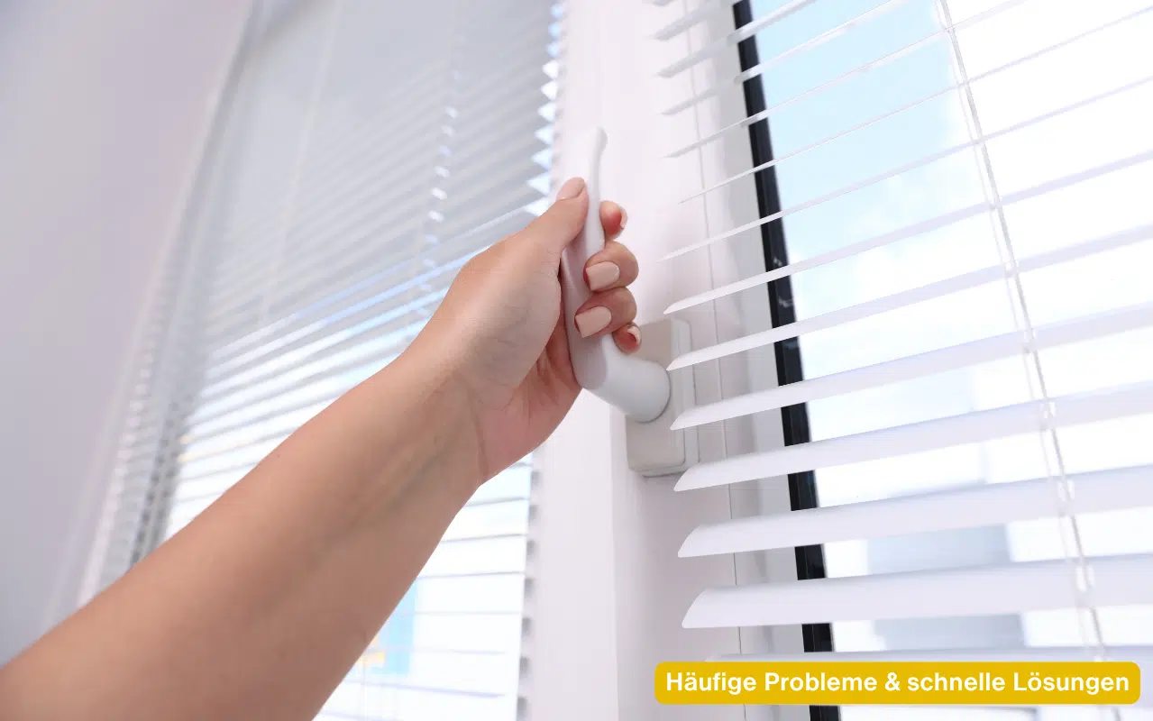 Häufige Probleme & schnelle Lösungen am Fenster verdeutlicht durch eine Hand am weißen Griff vor hellen Jalousien