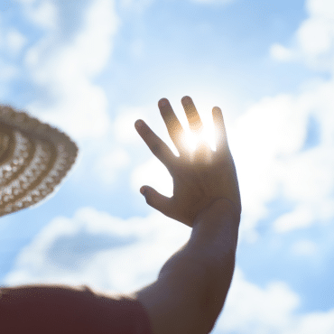 Hand schirmt grelle Sonne ab. Hitzeschutz für Fenster, so bleibt Ihr Zuhause im Sommer kühl.