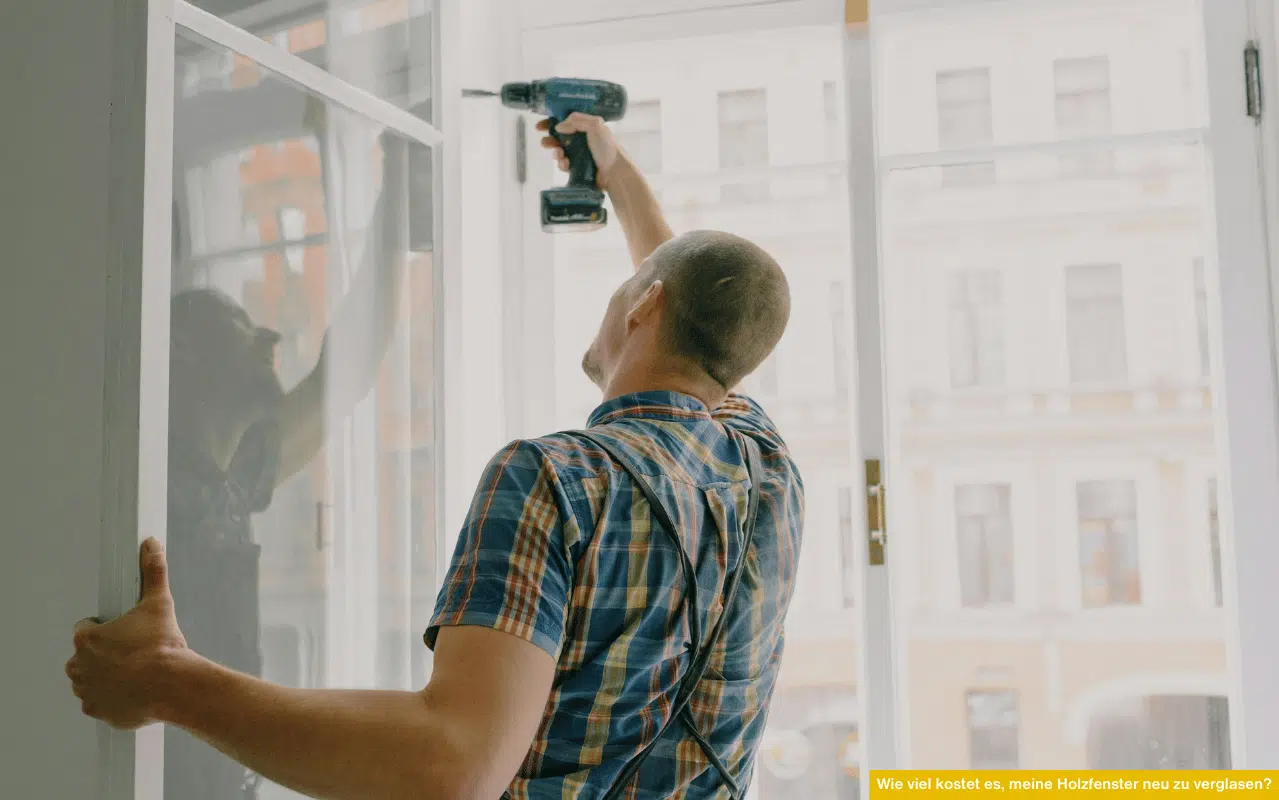 Handwerker montiert Glas in Holzrahmen. Wie viel kostet es, meine Holzfenster neu zu verglasen inklusive Montagekosten?