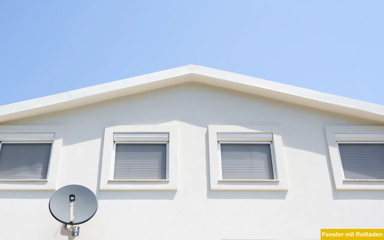 Giebelansicht eines Hauses mit hellen Fassadenfarben und grauen Rollladen an den Fenstern. Effektive Beschattung.
