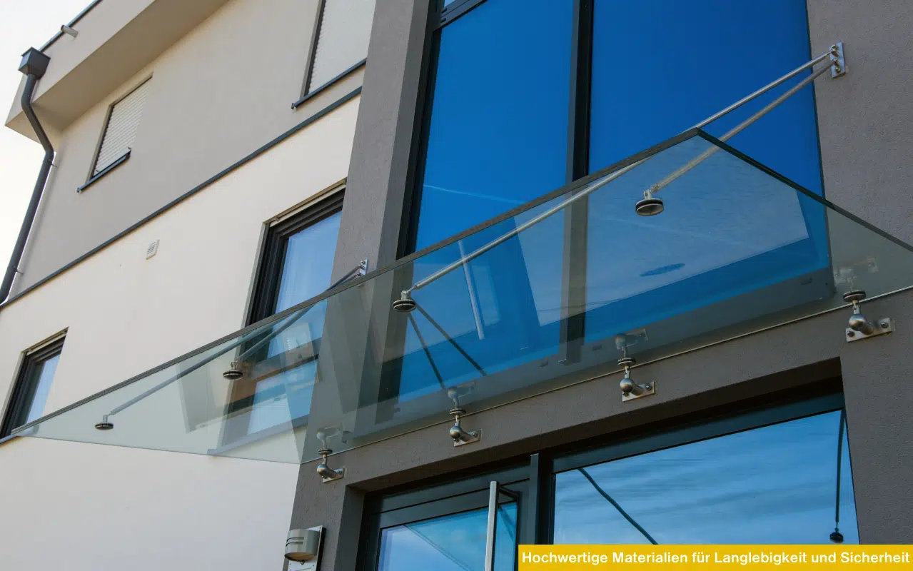 Ein modernes VSG-Glasvordach mit Edelstahl-Punkthaltern und Zugstangen vor einer blau verspiegelten Glasfassade.
