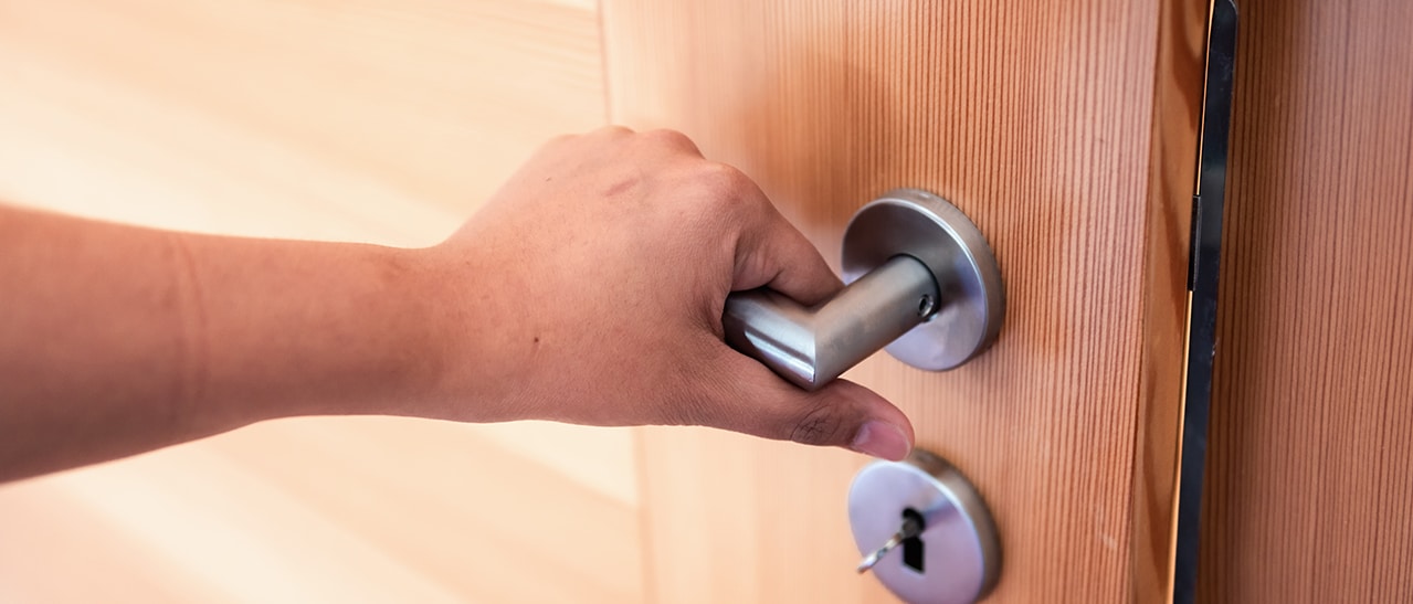 Hand am Türgriff – Holztüren verleihen dem Haus Wärme und Naturverbundenheit für ein gemütliches Heim.