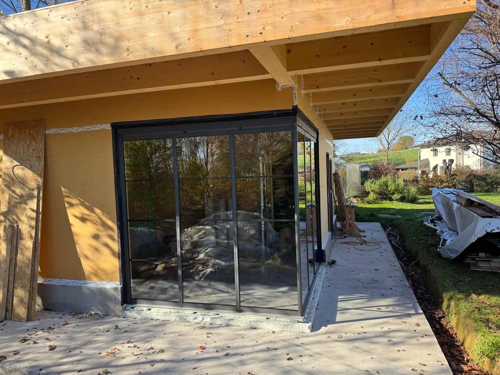 Isoliertes Gartenhaus in Holzbauweise mit Schiebe-Dreh-Verglasung und dunkelgrauen Sprossenrahmen