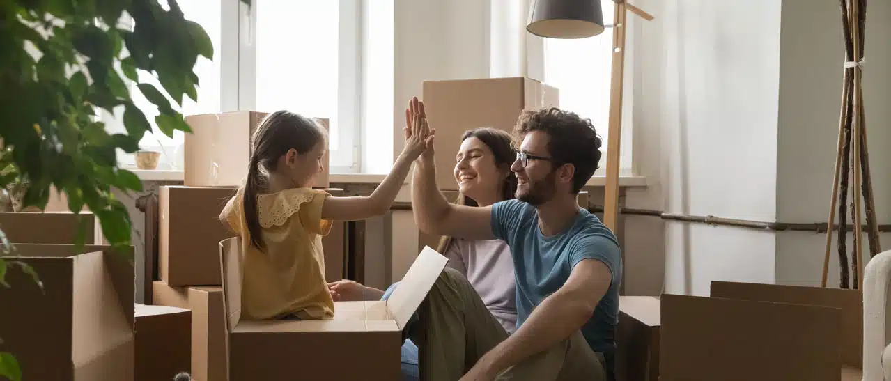 Junge Familie zieht in neue Wohnung mit modernen Wohnungsfenstern ein und freut sich auf Zuhause.