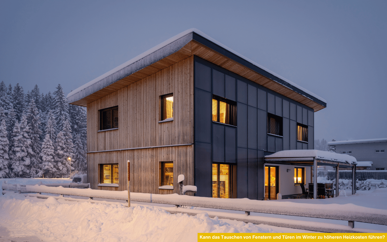 Das Foto zeigt ein modernes Einfamilienhaus im Winter mit eingeschneitem Dach. Durch die Fenster scheint warmes Licht, was die gute Wärmedämmung und Energieeffizienz neuer Fenster symbolisiert.