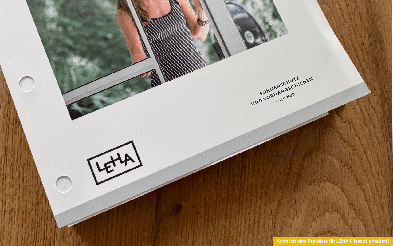 Kann ich eine Preisliste für LEHA Plissees erhalten? LEHA-Katalog für Sonnenschutzprodukte liegt auf einem Holztisch.