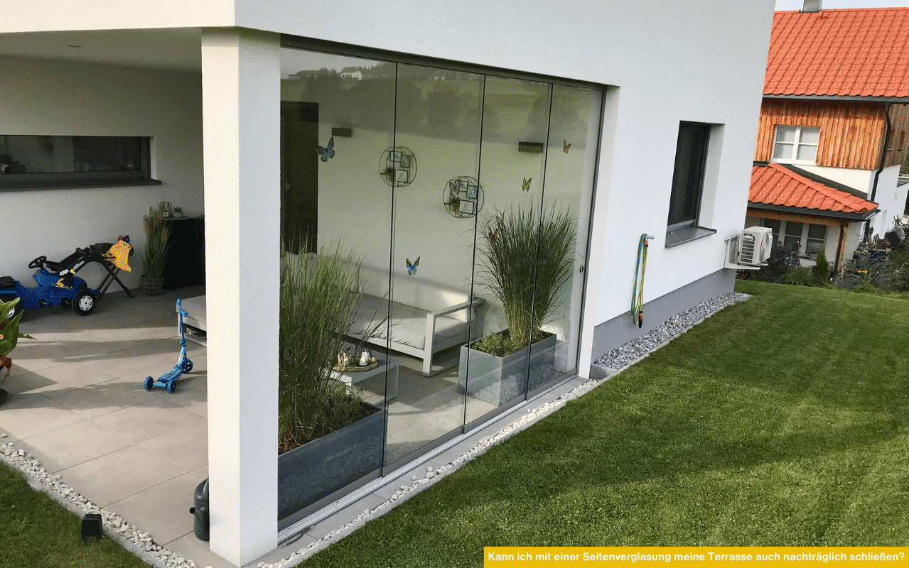 Das Bild zeigt eine moderne Terrasse mit Glas-Seitenverglasung, die als nachträglicher Wind- und Wetterschutz dient.
