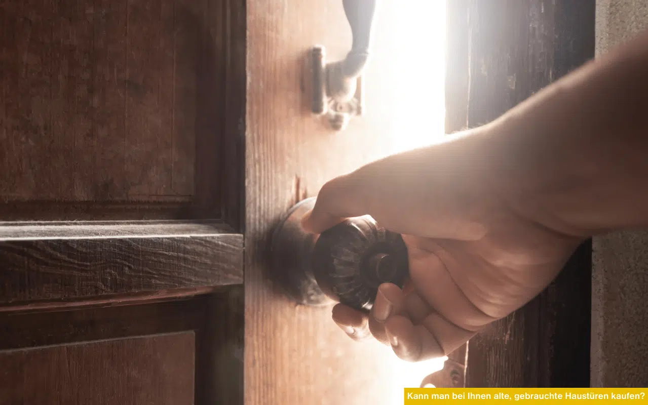 Kann man bei Ihnen alte, gebrauchte Haustüren kaufen Hand öffnet alte Holztür bei warmem Licht als Symbol für gebrauchte Türen