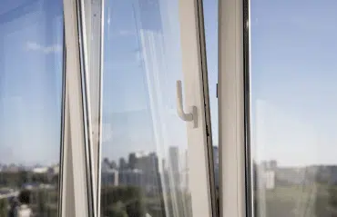 Kippfenster in weiß mit geöffnetem Flügel und Blick auf Stadtlandschaft