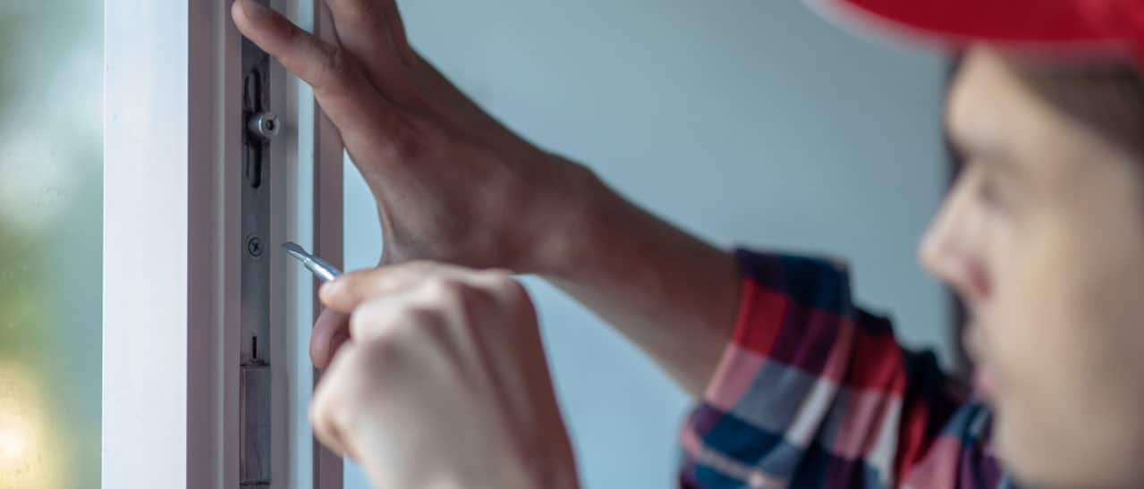 Handwerker bei Wartungsarbeiten an einem Fenster, Detailansicht seiner fachkundigen Arbeit.