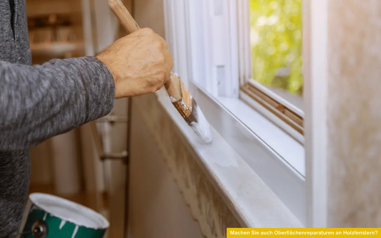 Machen Sie auch Oberflächenreparaturen an Holzfenstern Hand streicht weißen Rahmen eines Holzfensters zur Ausbesserung der Oberfläche