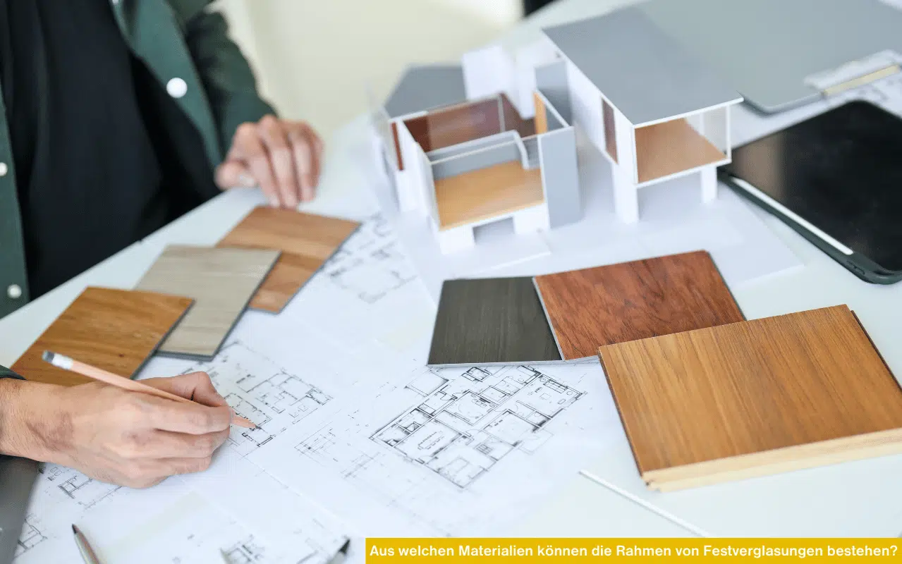 Beratungssituation mit Materialproben in Holzoptik, Bauplänen und einem Architekturmodell für Fensterrahmen.