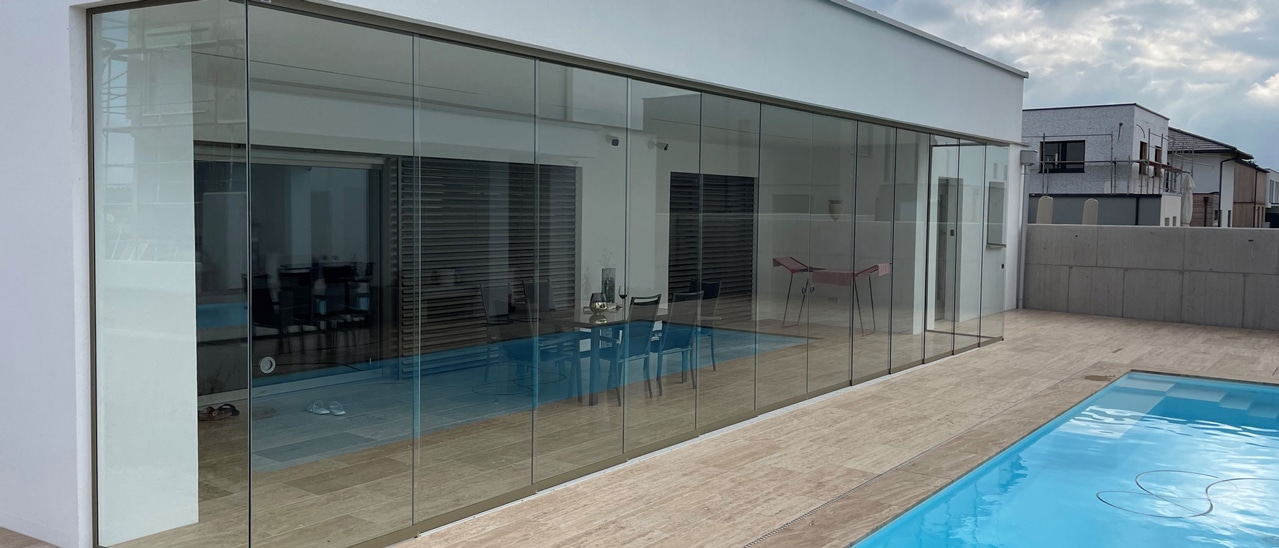 Moderne Glasschiebewand schließt überdachten Terrassenbereich in Neubau, Linz Land.