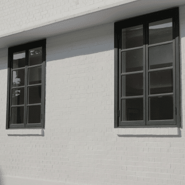 Moderne Fenster in RAL 9011 Graphitschwarz an weißer Hausfassade zeigen stilvolle Kontraste und zeitgemäßes Design im Altbau oder Neubau.