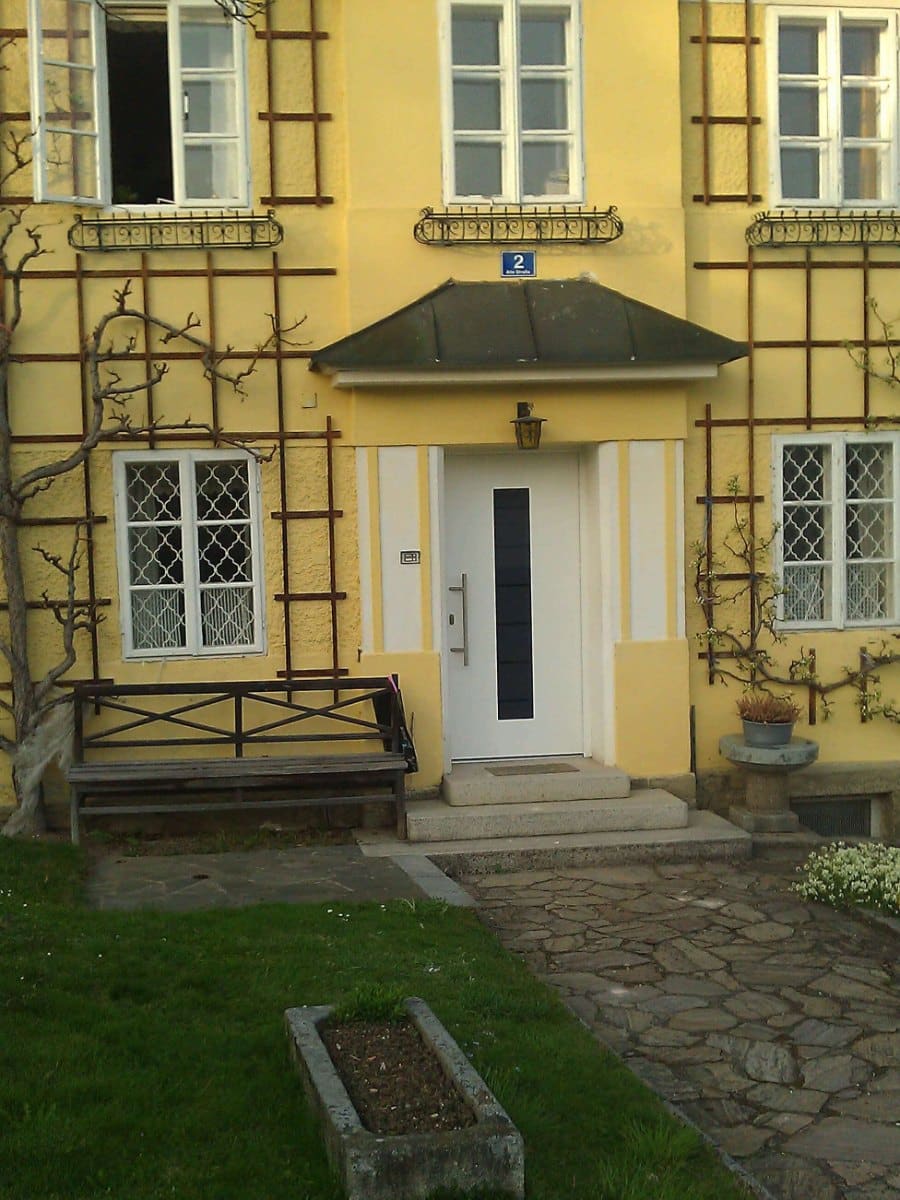 Moderne weiße Haustür mit schmalem Glasstreifen in einem gelben Altbau