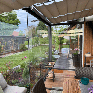 Moderne Pergola in Oberösterreich mit Glaswänden und Holzdetails – stilvolle Wohnraumerweiterung mit Blick in den Garten.