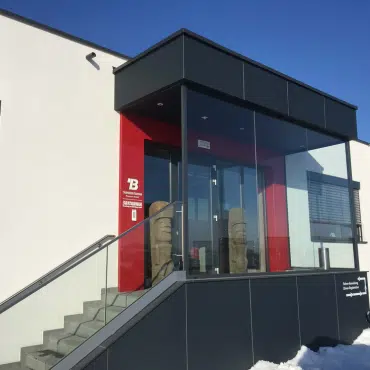 Moderner Windfang am Hauseingang aus Glas und Aluminium als Vorbau bietet Wetterschutz und stilvolle Gestaltung für den Eingangsbereich eines Gebäudes