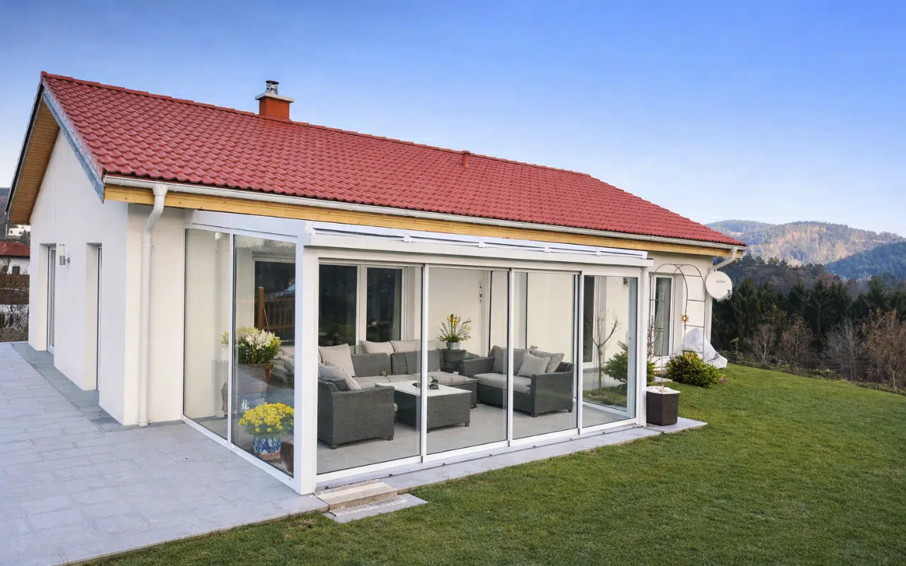 Moderner Wintergarten mit großer Glasfront an einem Wohnhaus bietet einen lichtdurchfluteten Wohnbereich im Grünen.