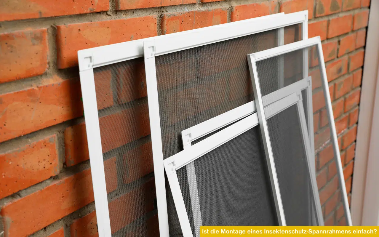 Drei weiße Insektenschutz-Spannrahmen lehnen montagefertig an einer roten Ziegelwand mit gelbem Infobalken.