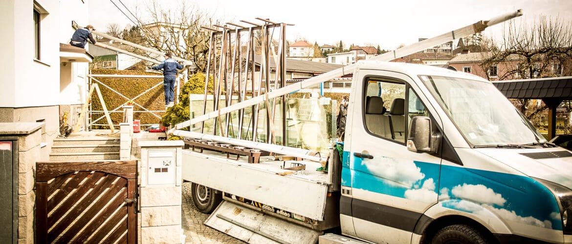 Monteure bei der Montage einer Terrassenverglasung in Linz, ausgeführt von Fenster-Schmidinger. Montagedauer variiert je nach System und Extras.