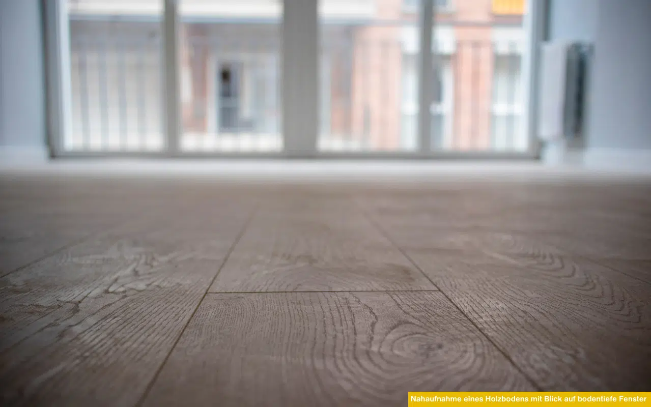 Nahaufnahme eines Holzbodens mit Blick auf bodentiefe Fenster – symbolisiert die Gefahr von UV-bedingtem Ausbleichen durch starke Sonneneinstrahlung.