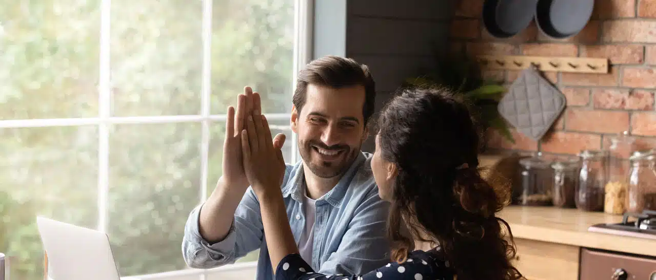Glücklicher Familienvater und Frau feiern ihren Kauf von Sicherheitsfenstern mit High-Five.