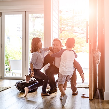 Familienvater öffnet Alu-Nebeneingangstür, Kinder rennen ihm freudig entgegen.