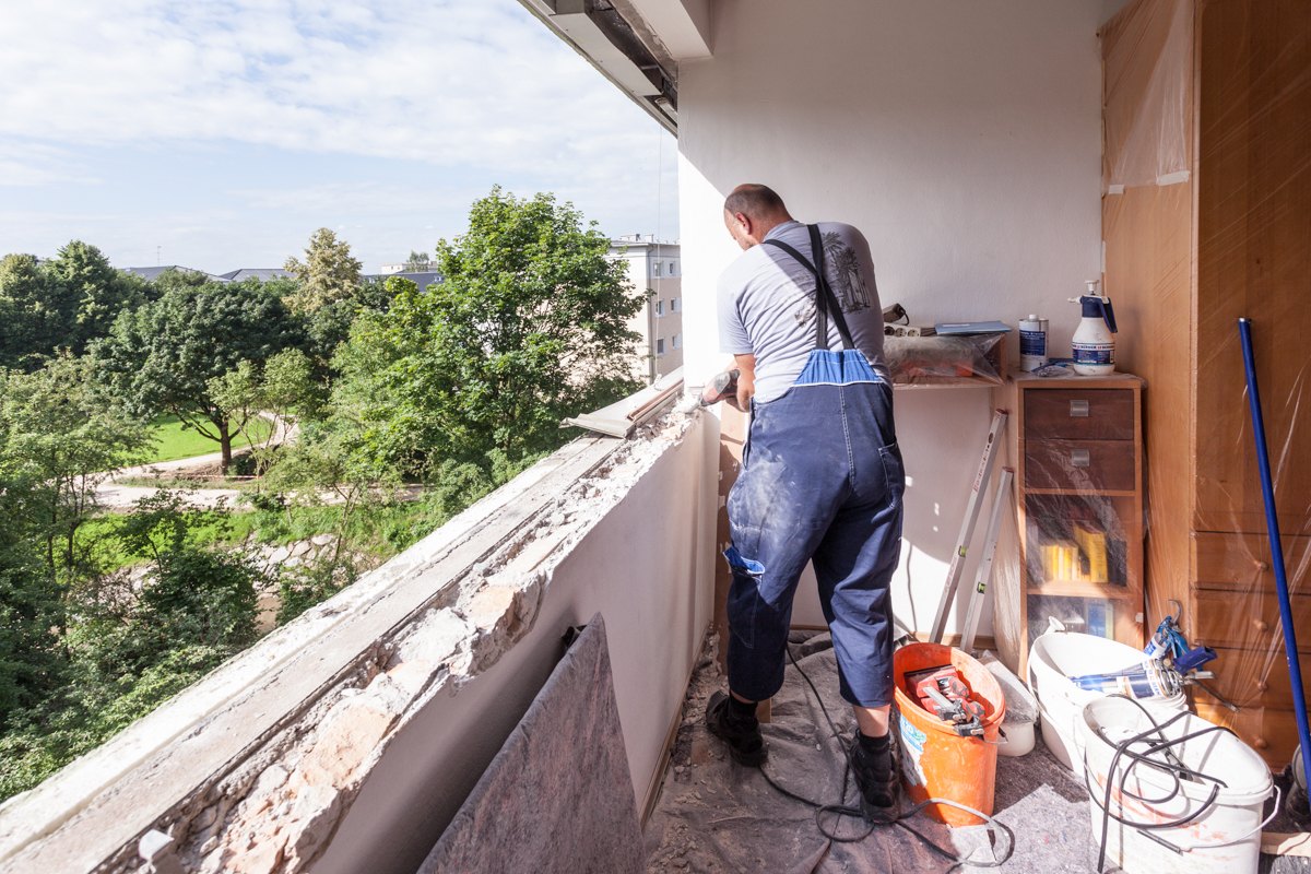 Monteur stemmt den alten Fensterstock aus der Laibung, Demontage beim Fenstertausch