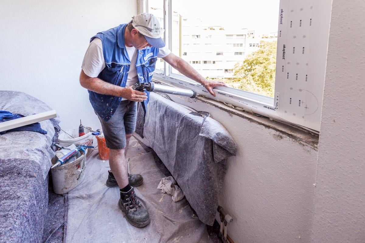 Monteur dichtet den unteren Fensteranschluss innen ab, luftdichte Ebene nach ÖNORM B 5320