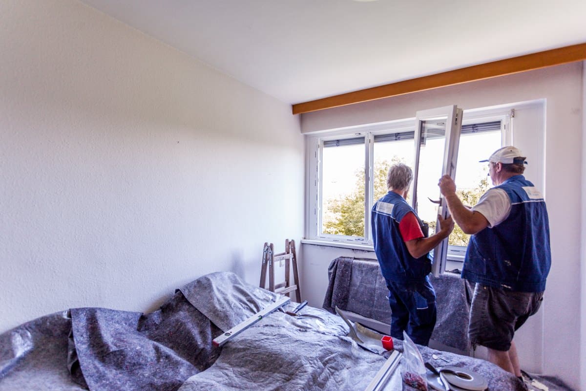Zwei Monteure hängen den Fensterflügel in den montierten Rahmen ein