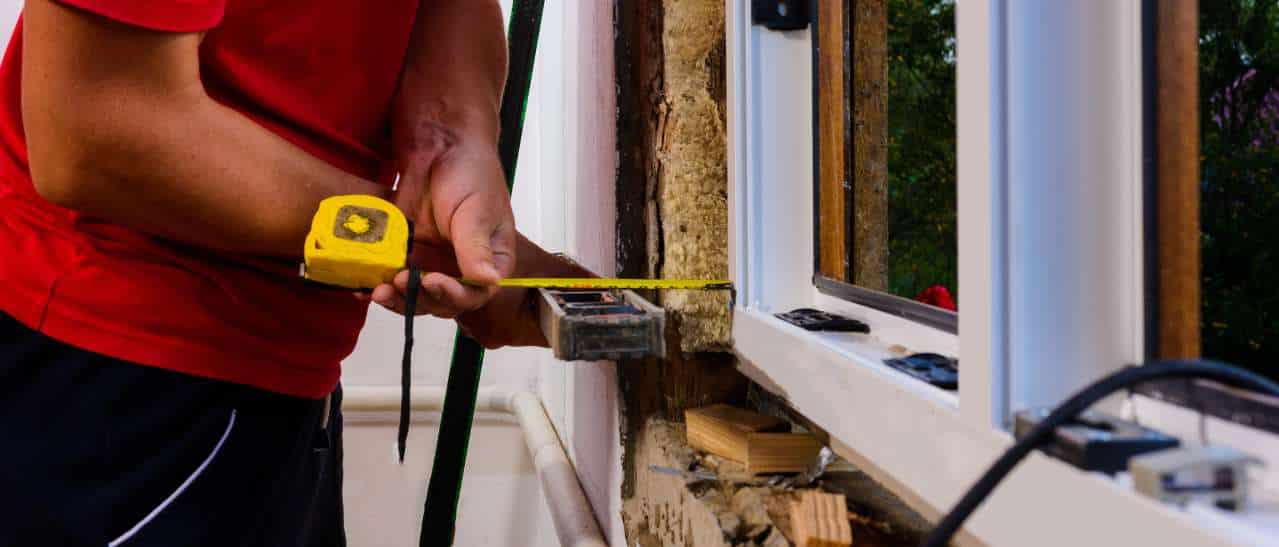 Fenstermonteur beim Ausrichtigen der Fensterposition im Mauerwerk