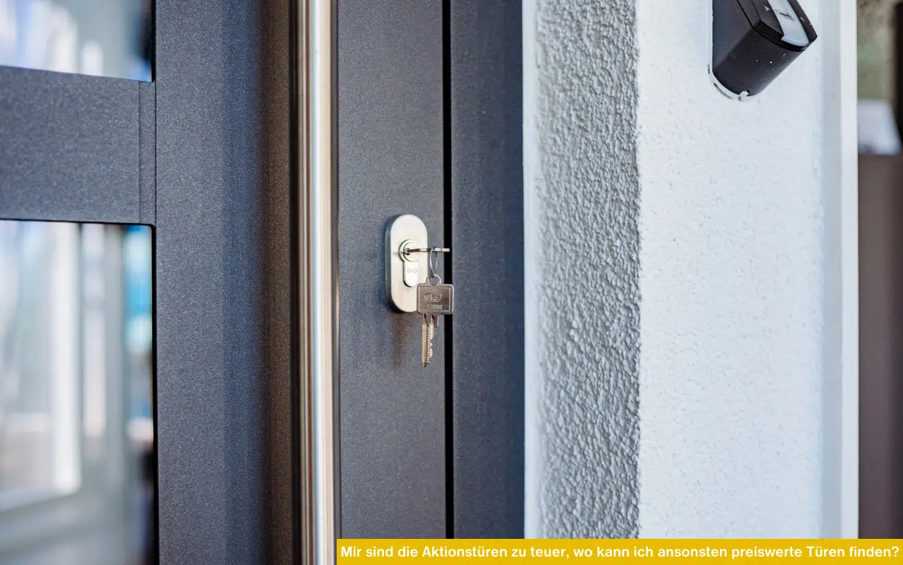 Nahaufnahme eines Haustürschlosses mit steckendem Schlüssel in einer modernen, anthrazitfarbenen Tür.