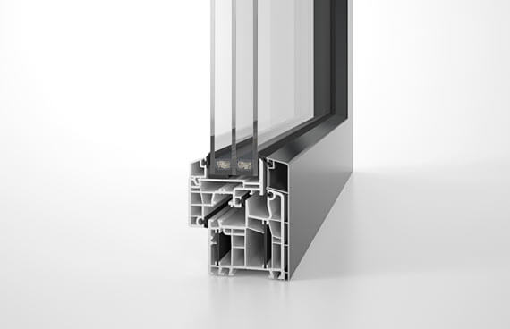 Profilquerschnitt eines Designfensters mit Dreifachverglasung, weißem Kunststoff-Mehrkammersystem und dunkler Außenschale.