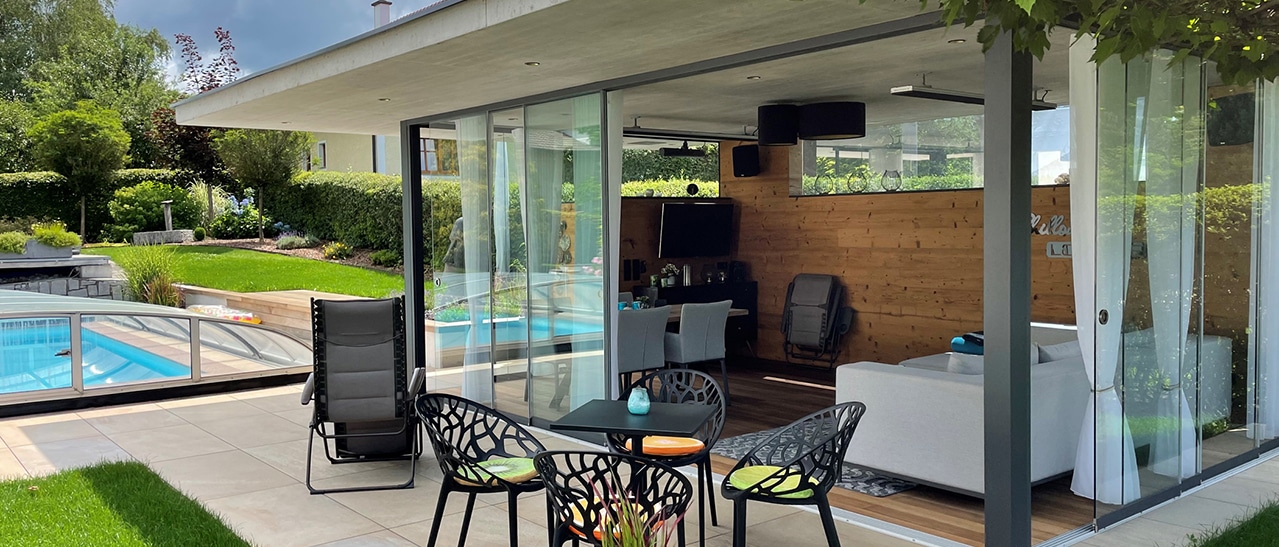 Rahmenlose Glas-Schiebetüren von Sunflex SF 20 an einem Poolhaus im Garten - freier Blick durch großflächige Glasflächen ohne sichtbare Rahmenkonstruktion