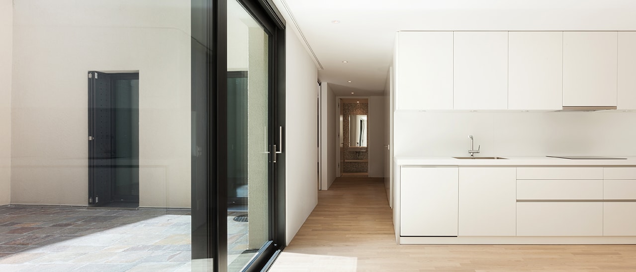Beispiel für Sanierung mit großen Glas-Schiebetüren, die Küche und Wohnbereich öffnen und Licht sowie direkten Zugang zur Terrasse schaffen.