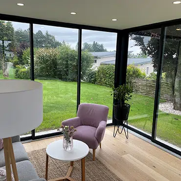 Moderner Wohnraum mit Glasfront und Blick ins Grüne – stilvolle Wohnraumerweiterung mit geschlossenem Flachdach und Schiebesystem.