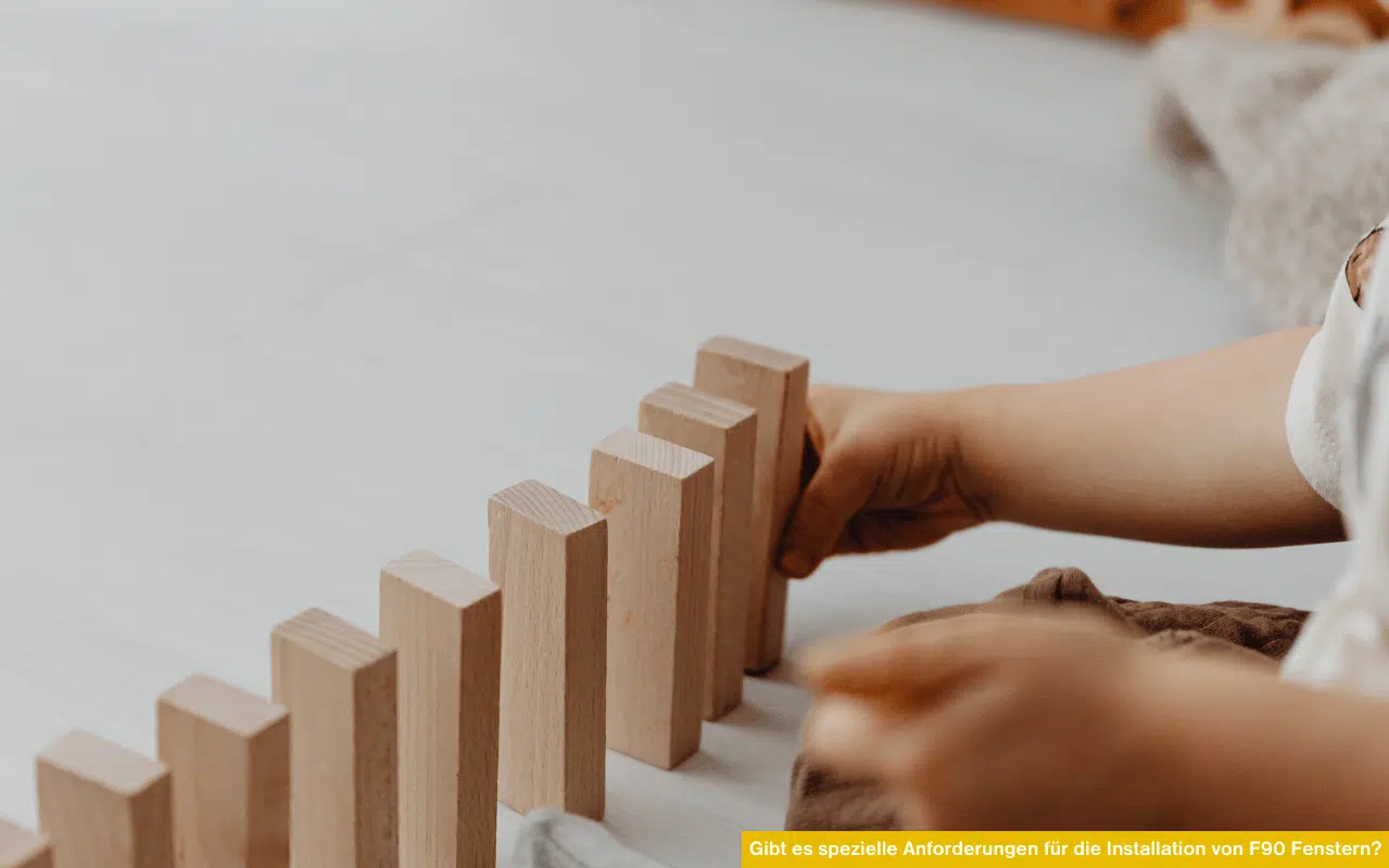 Reihe aus Holzklötzen wird aufgebaut und steht sinnbildlich für „Gibt es spezielle Anforderungen für die Installation von F90 Fenstern?“