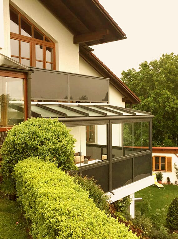 Balkonverglasung und Glasgeländer in grau an einem Wohnhaus mit Glasdach