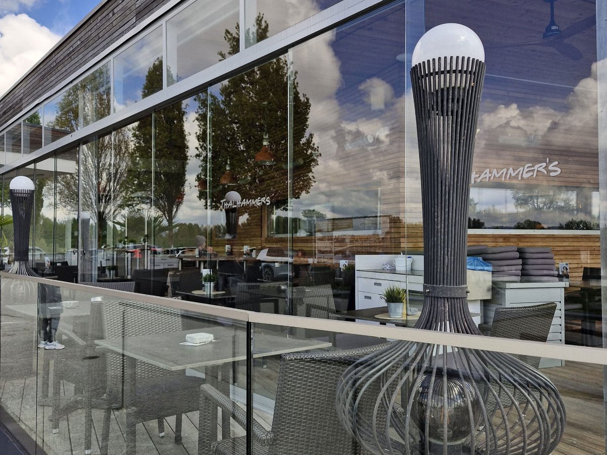 Blick durch die Glasschiebetüren auf die überdachte Terrasse des Seerestaurants