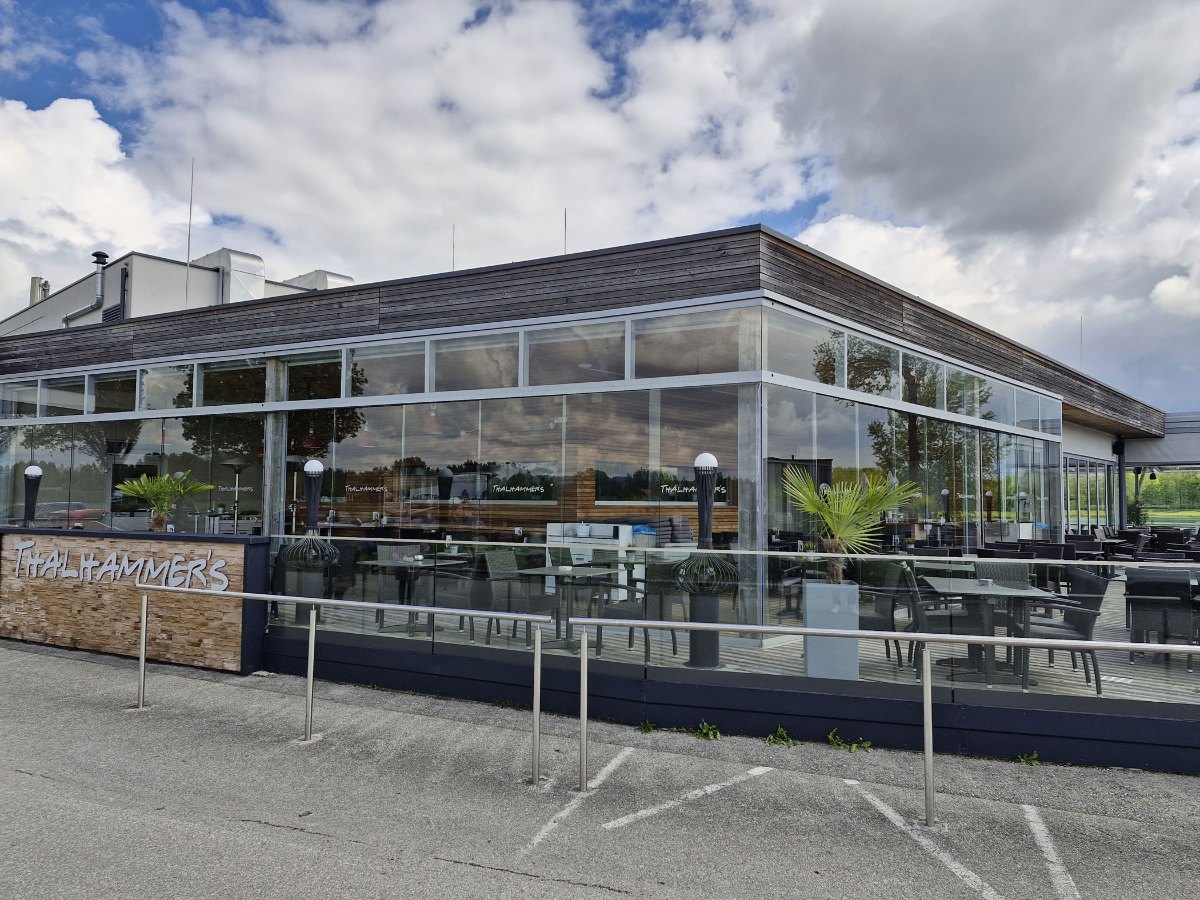 Ganzglas-Schiebesystem als Wind- und Wetterschutz an der Terrasse eines Seerestaurants in Oberösterreich