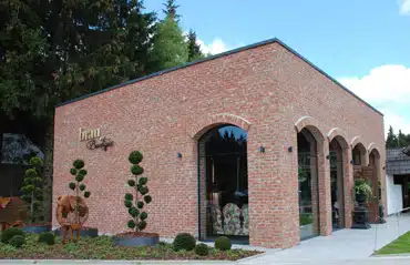 Segmentbogenfenster in Oberösterreich bei einem modernen Ziegelbau mit stilvoller Fassadengestaltung und dekorativen Pflanzen.