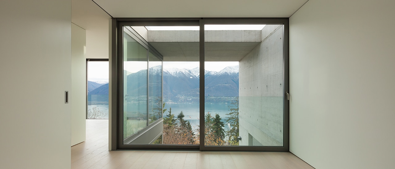 Setzen Sie mit dunklen Fensterrahmen den Ausblick in Szene Bild zeigt Raum mit Fenstern, Blick auf See und Berge, dunkle Rahmen heben Natur hervor.