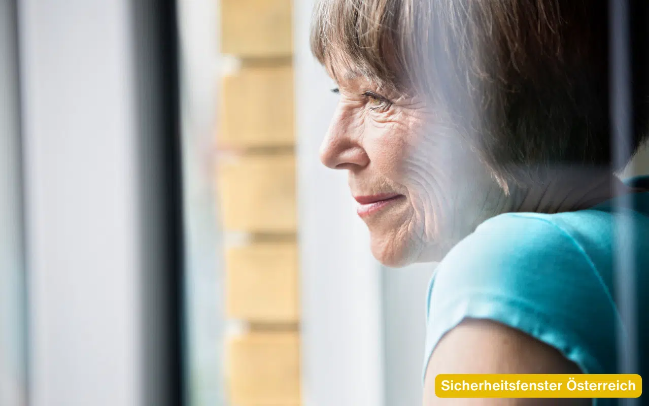 Sicherheitsfenster Österreich – Frau am Fenster genießt ein sicheres Wohngefühl mit modernem Einbruchschutz