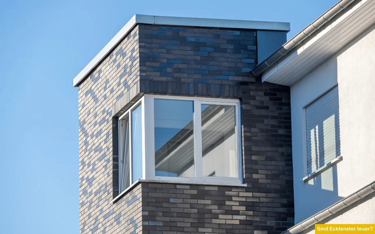 Sind Eckfenster teuer? Auskragendes Eckfenster mit weißem Rahmen an dunkler Klinkerfassade