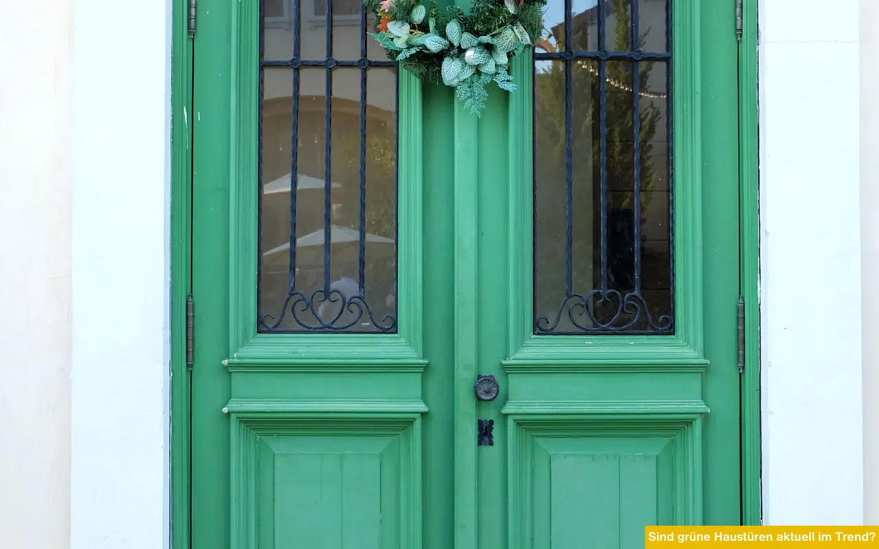 Sind grüne Haustüren aktuell im Trend? Klassische grüne Haustür mit Glasfeldern und Ziergitter an heller Fassade