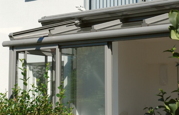 Die Ansicht zeigt das Dachsystem eines Sommergartens von außen. Die präzise Verarbeitung der grauen Metallprofile und die funktionalen Beschattungseinheiten verdeutlichen eine hochwertige Lösung für ein komfortables Wohnen im Freien.