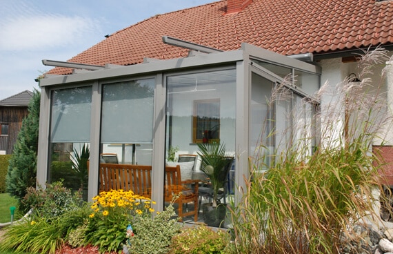 Gemütlicher Sommergarten aus Aluminium mit Glasflächen, Sitzbank und Pflanzen für entspanntes Wohnen im Grünen