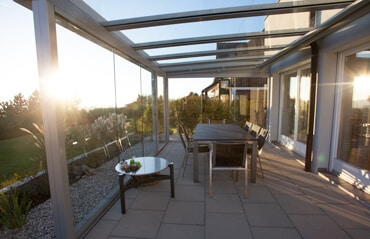 Sommergarten mit Glasschiebetüren bei Sonnenuntergang, ideal um die Seele baumeln zu lassen.